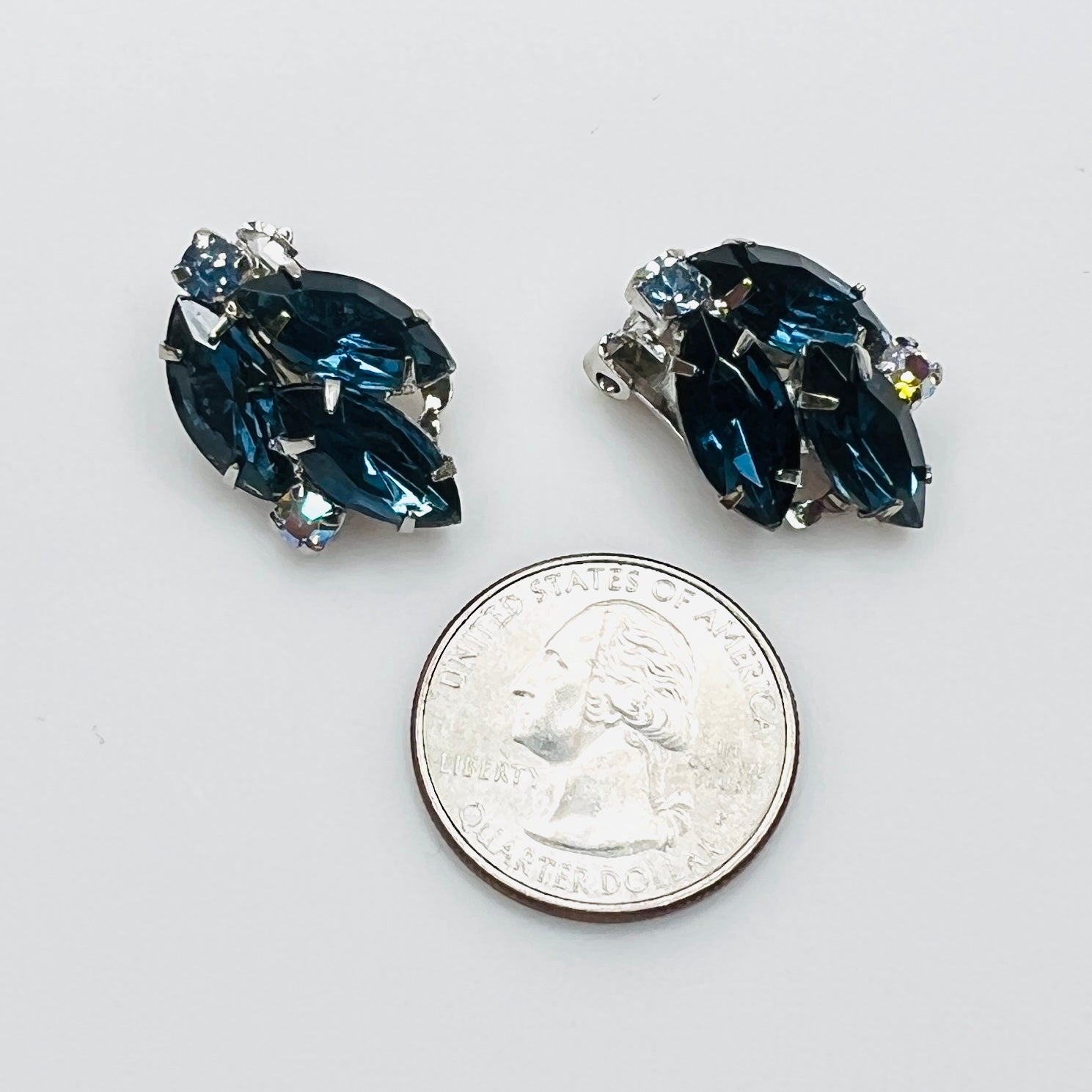 Blue rhinestone clip-on earrings beside a quarter for size reference.