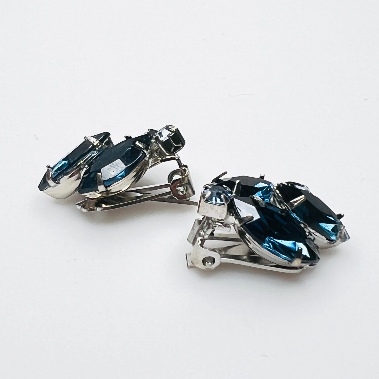 Side view of vintage blue rhinestone clip-on earrings showing silver-tone settings.
