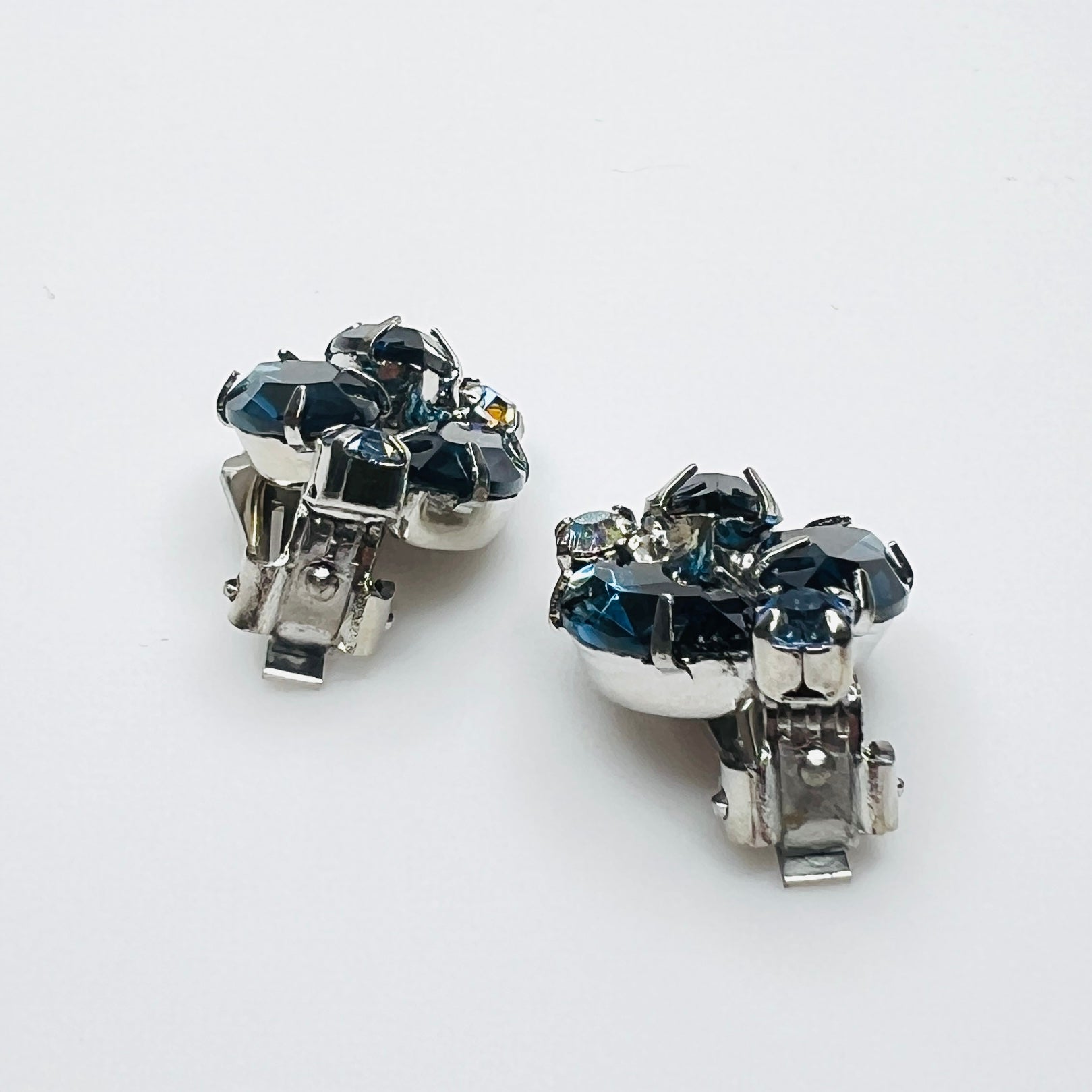 Side view of vintage blue rhinestone clip-on earrings showing silver-tone settings.