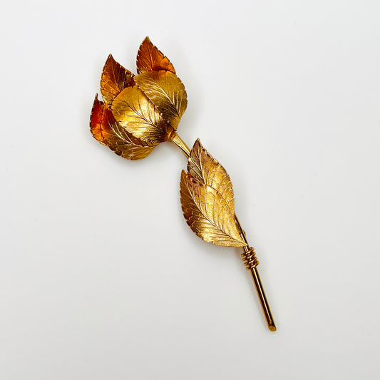 Vintage signed Coro gold-tone long stem rose brooch with textured petals and leaves.
