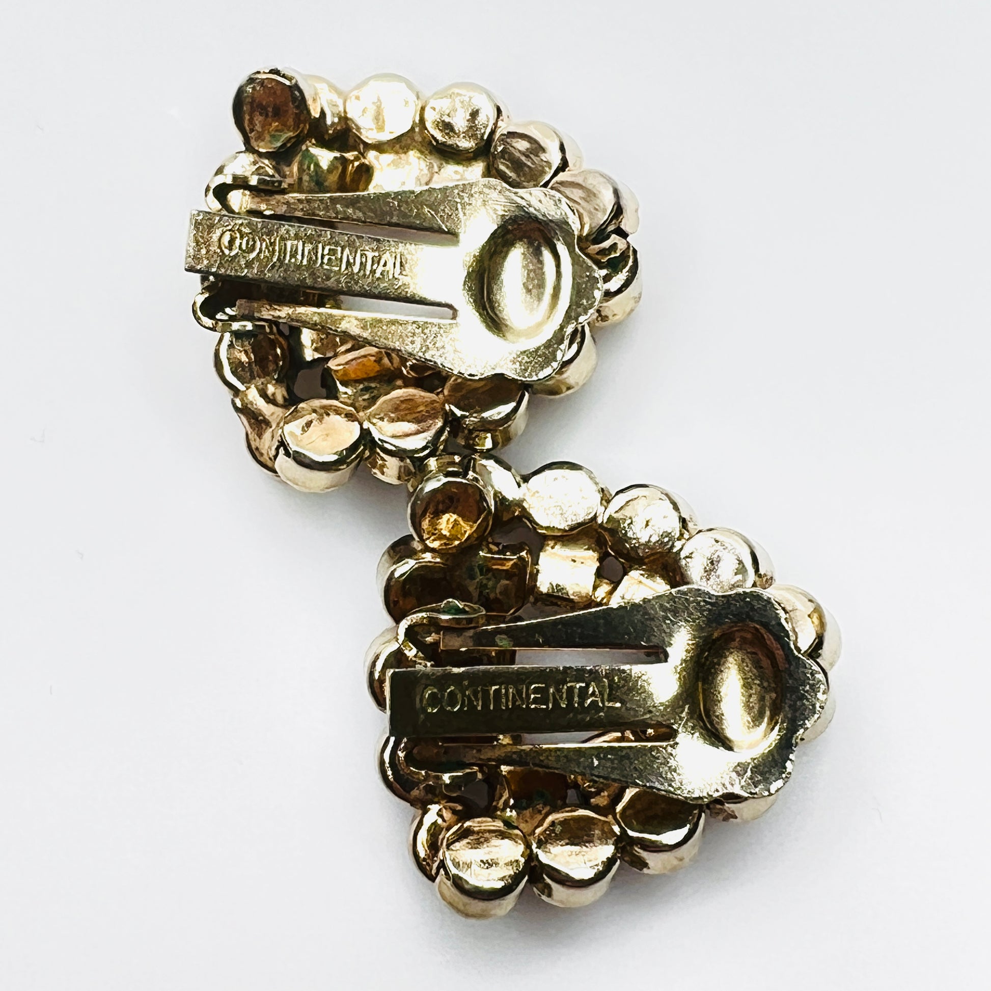 Close up of signature for signed Continental gold-tone clip-on earrings.