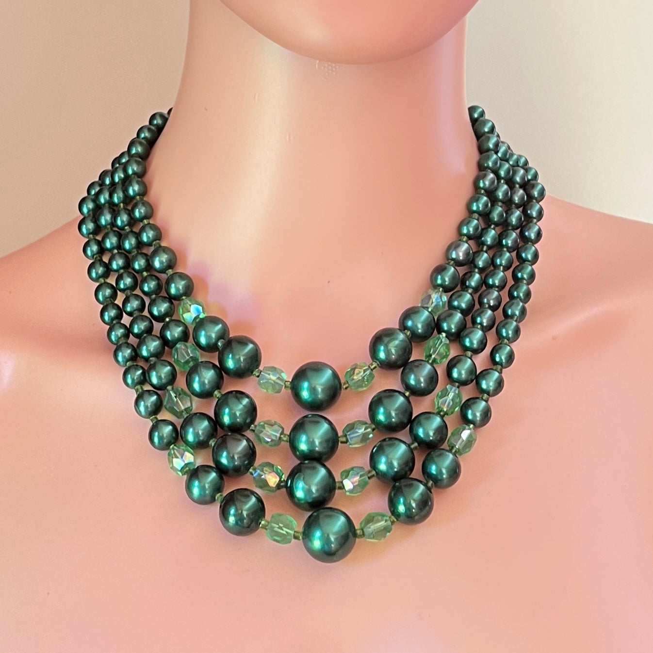 Multi strand emerald green faux pearl necklace displayed on mannequin