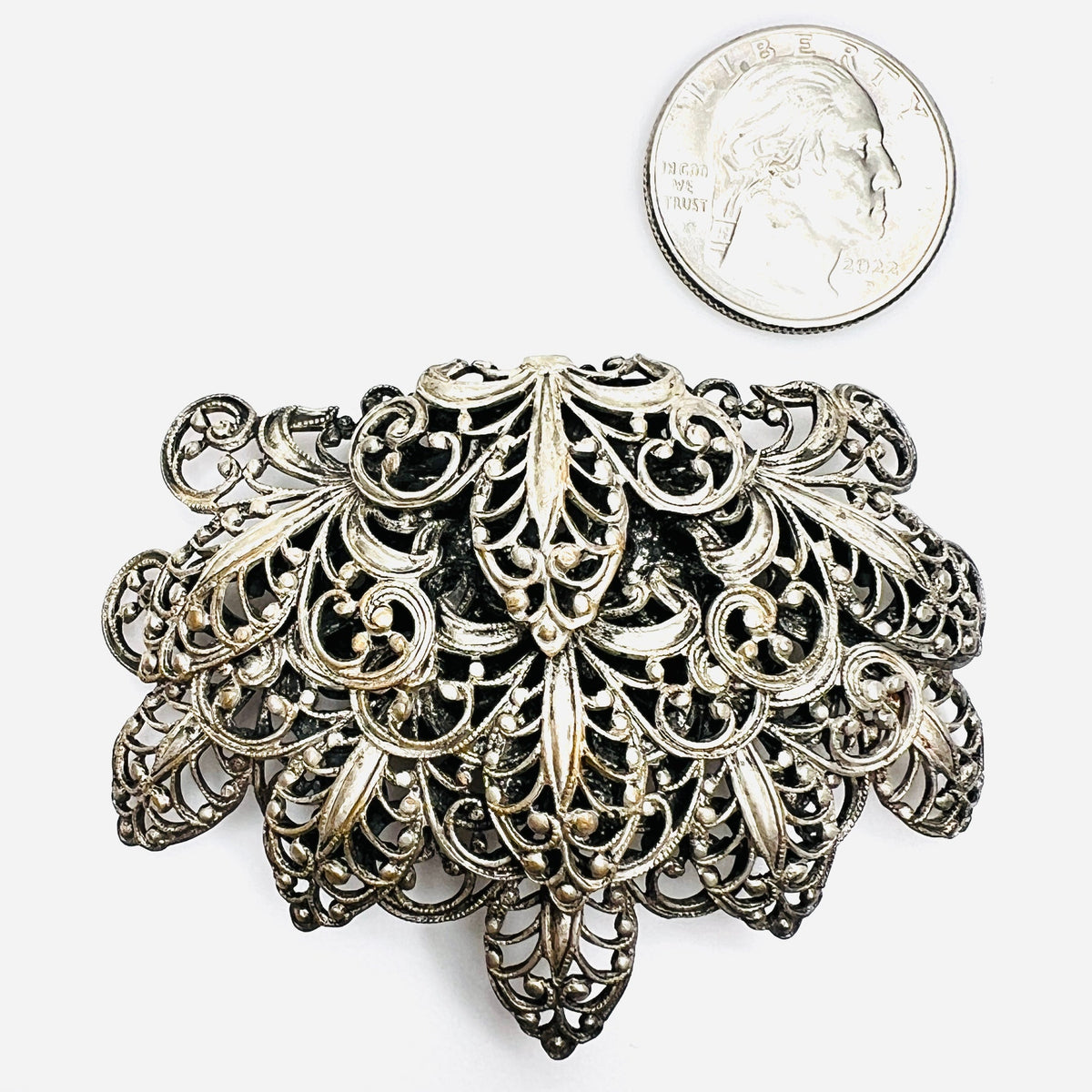 Large silver tone 1950s filigree brooch shown with quarter for scale