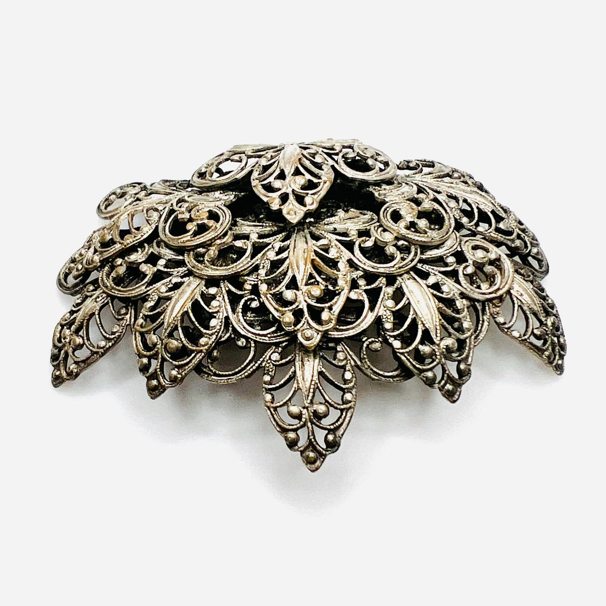 Side view of vintage silver tone filigree brooch showing dimensional layered construction