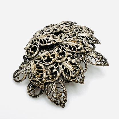 Side view of vintage silver tone filigree brooch showing dimensional layered construction