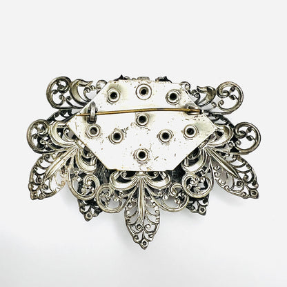 Reverse of 1950s silver tone filigree brooch showing rivet construction and pin closure
