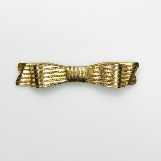 Vintage 1950s gold-tone bow brooch with elongated ribbon shape, textured ridges, and polished accents