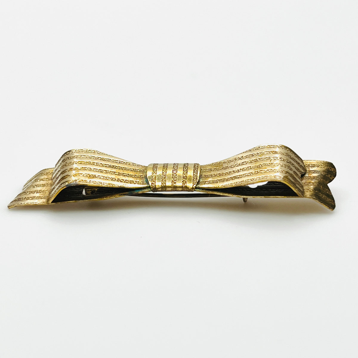 Side view of 1950s textured gold-tone bow pin showing layered ribbon loops and dimensional construction