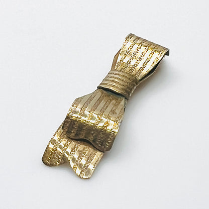 Side view of 1950s textured gold-tone bow pin showing layered ribbon loops and dimensional construction