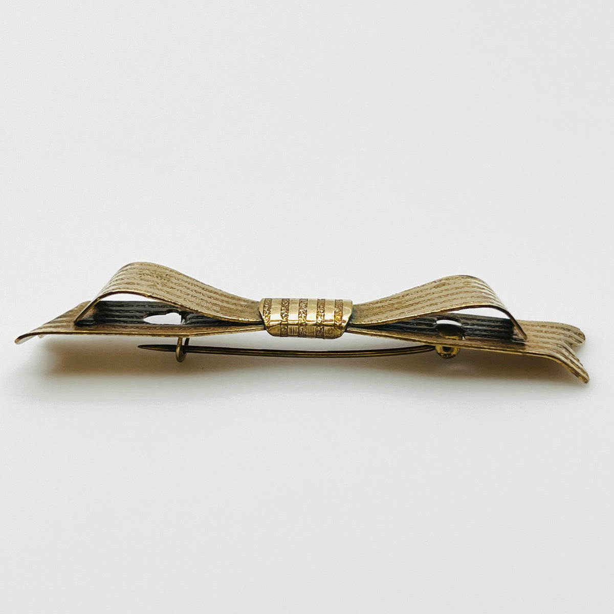 Side view of 1950s textured gold-tone bow pin showing layered ribbon loops and dimensional construction