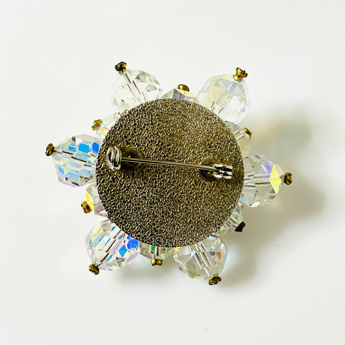 Reverse of vintage crystal cluster brooch showing textured silver-tone backing and pin clasp