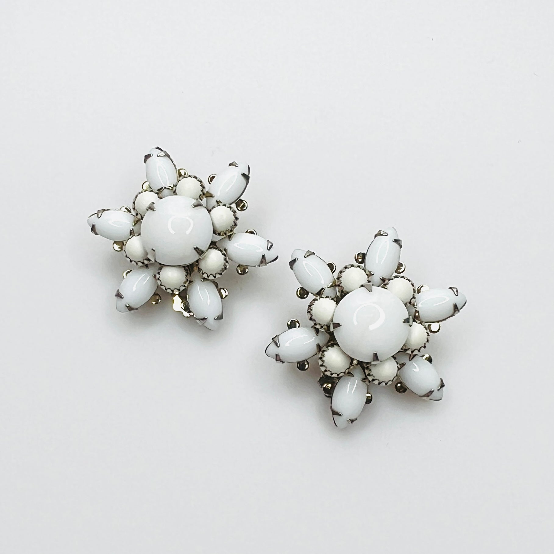 Vintage 1950s white milk glass flower clip-on earrings with floral cluster design.