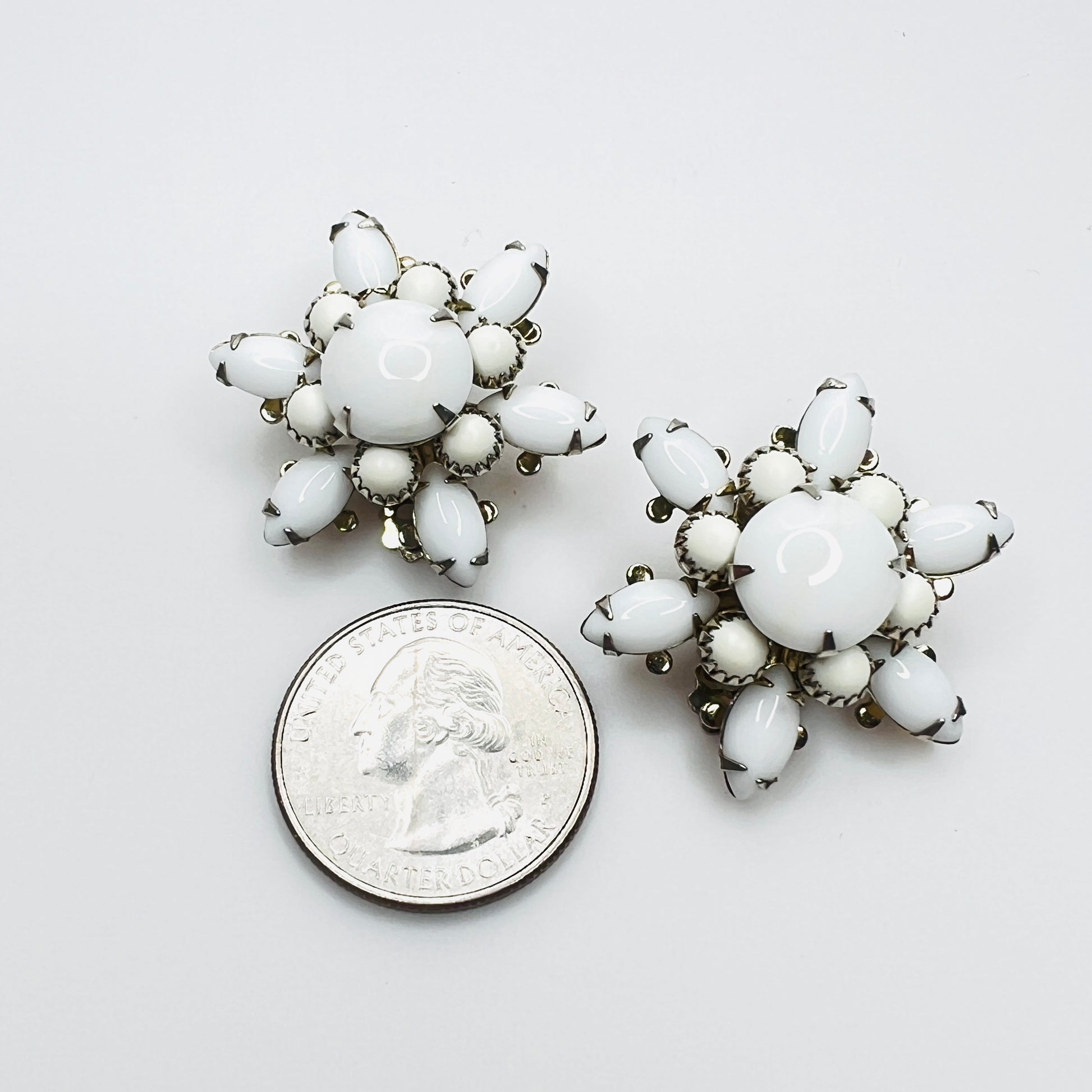 White milk glass floral clip-on earrings shown with quarter for size.
