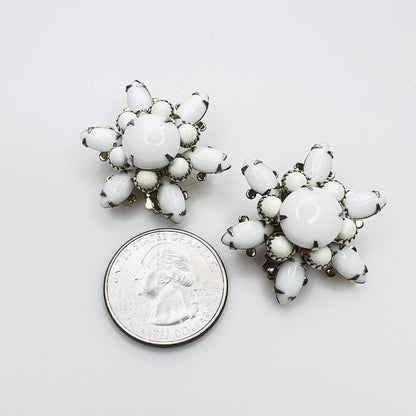 White milk glass floral clip-on earrings shown with quarter for size.