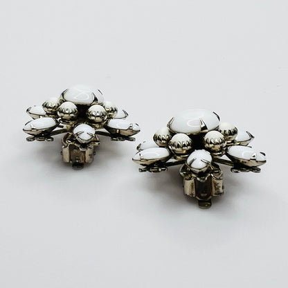 Side view of vintage milk glass flower clip-on earrings in silver-tone setting.