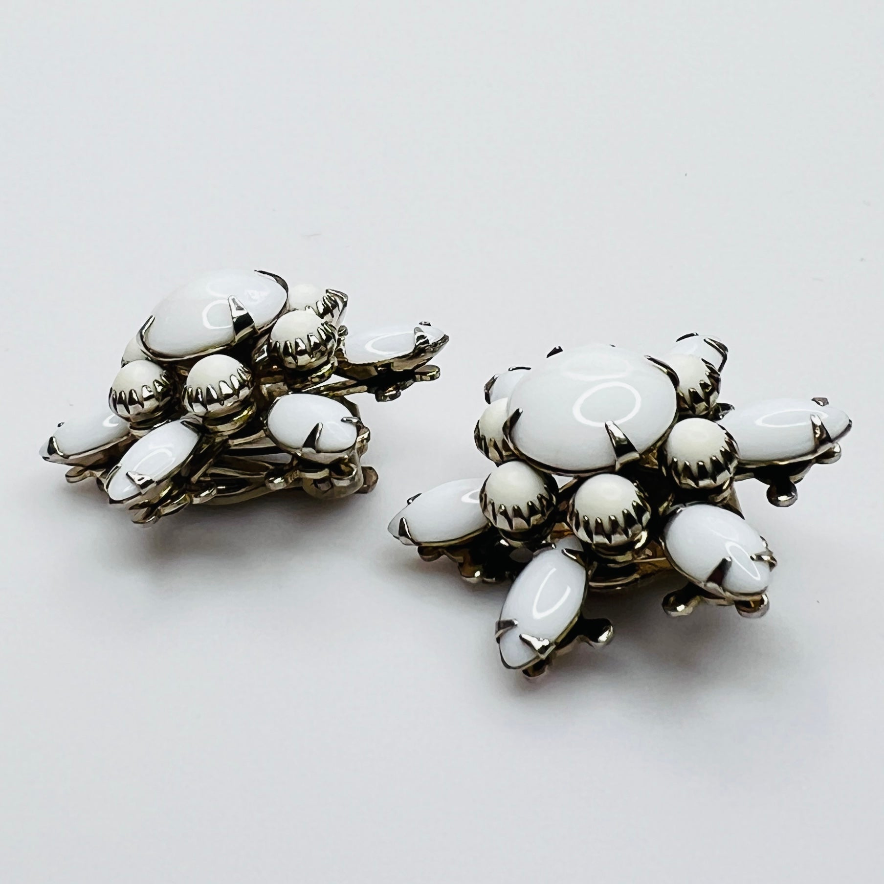 Side view of vintage milk glass flower clip-on earrings in silver-tone setting.