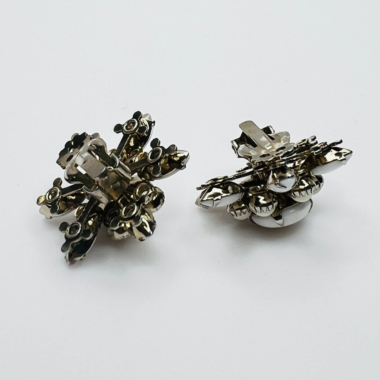 Side view of vintage milk glass flower clip-on earrings in silver-tone setting.