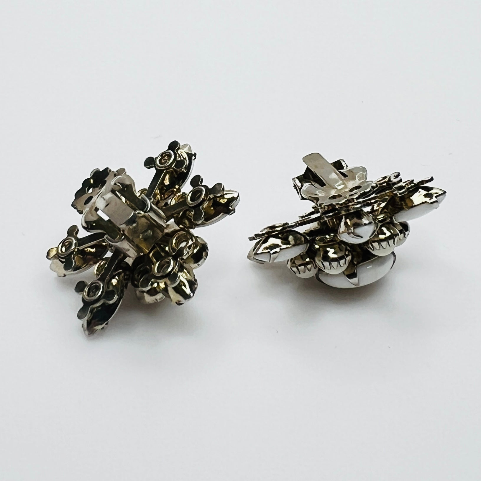 Side view of vintage milk glass flower clip-on earrings in silver-tone setting.