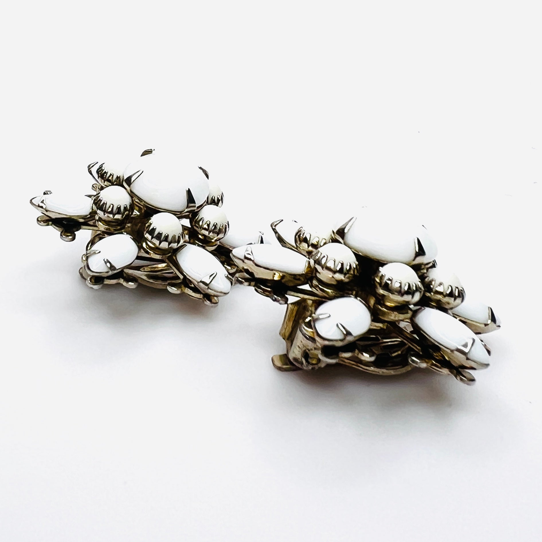 Side view of vintage milk glass flower clip-on earrings in silver-tone setting.