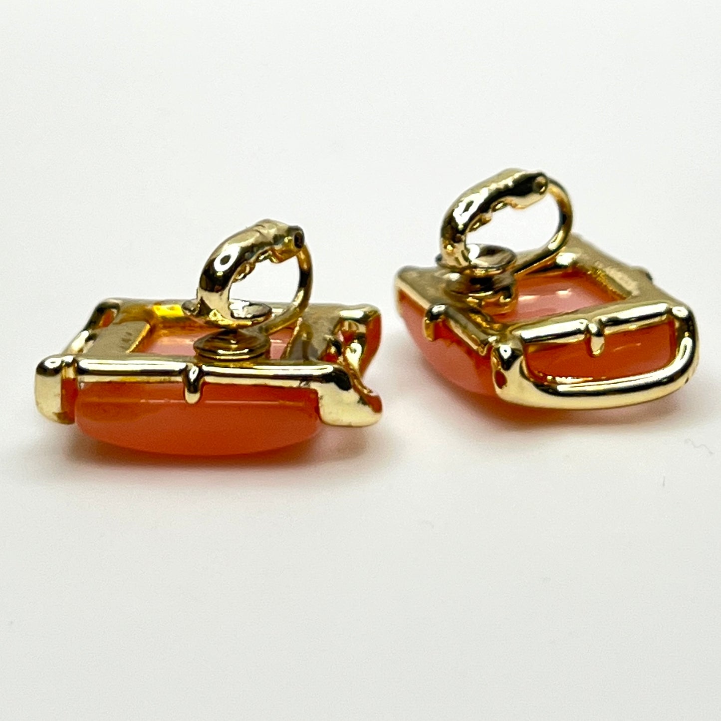Side view of vintage pink thermoset Lucite clip-on earrings in gold-tone metal