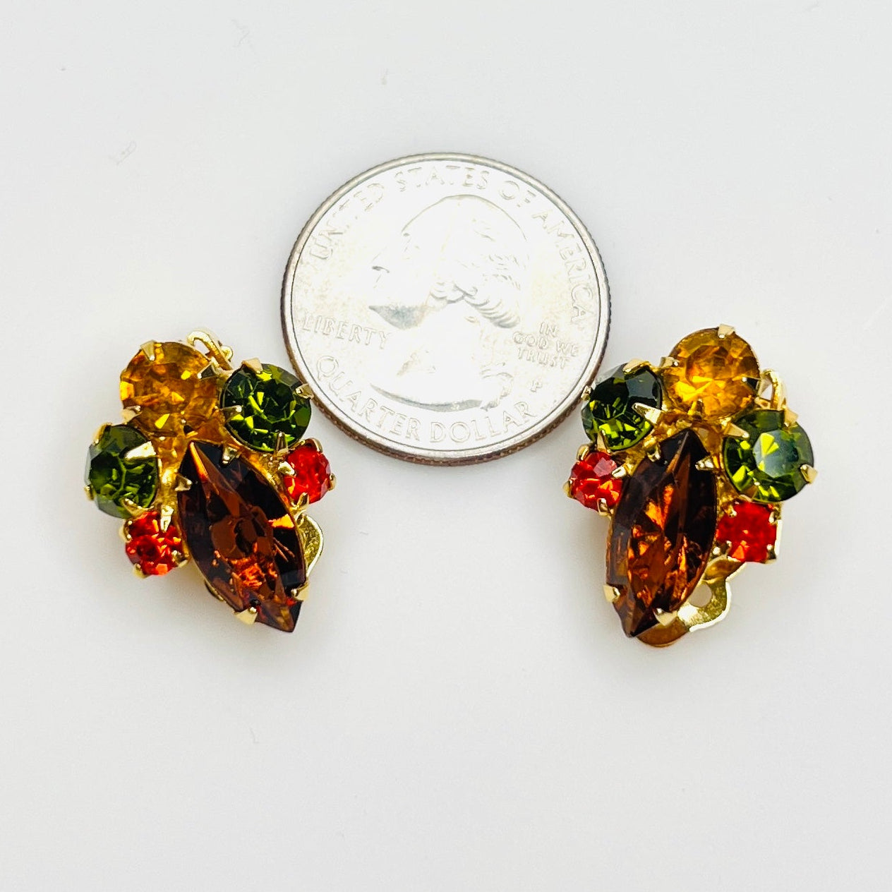 Colorful vintage rhinestone clip earrings shown with quarter for size.