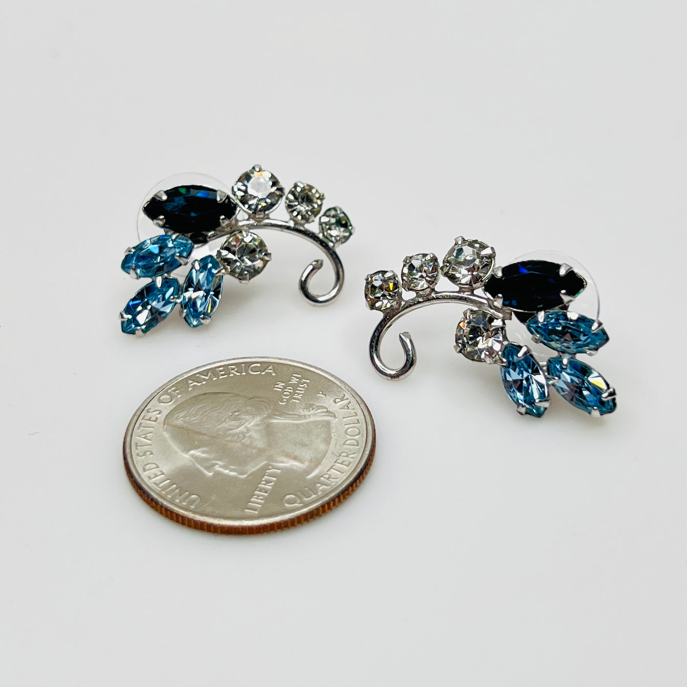 Mid-century blue and clear rhinestone earrings beside quarter for scale