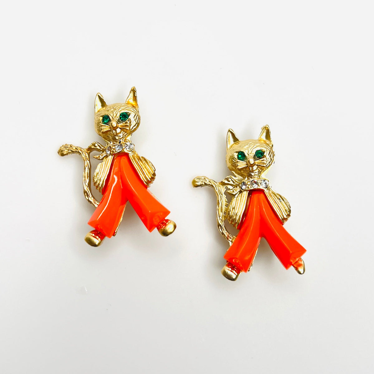 Pair of 1950s gold-tone cat brooches with coral Lucite pants, green rhinestone eyes and sparkling collars