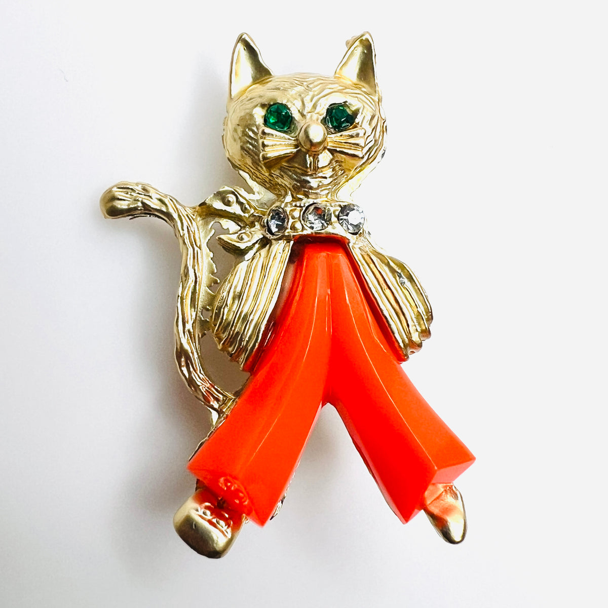 Close-up of 1950s gold-tone cat brooch with green rhinestone eyes and coral Lucite pants
