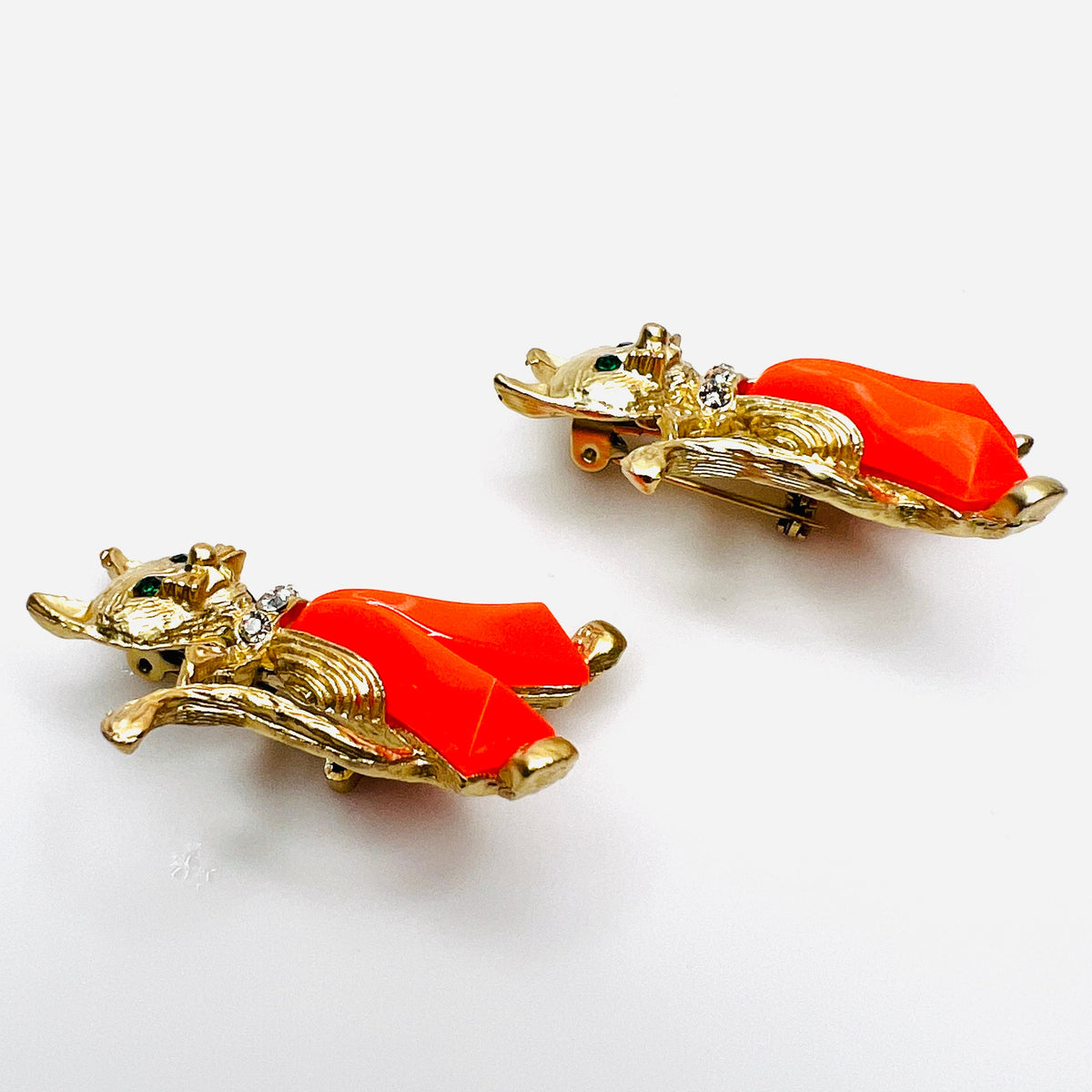 Angled view of two vintage figural cat brooches with dimensional coral Lucite trousers