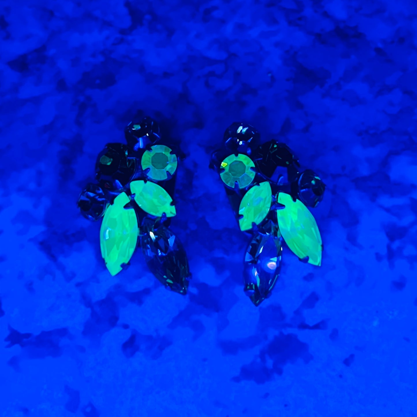 Vintage uranium glass earrings glowing bright green under UV blacklight.