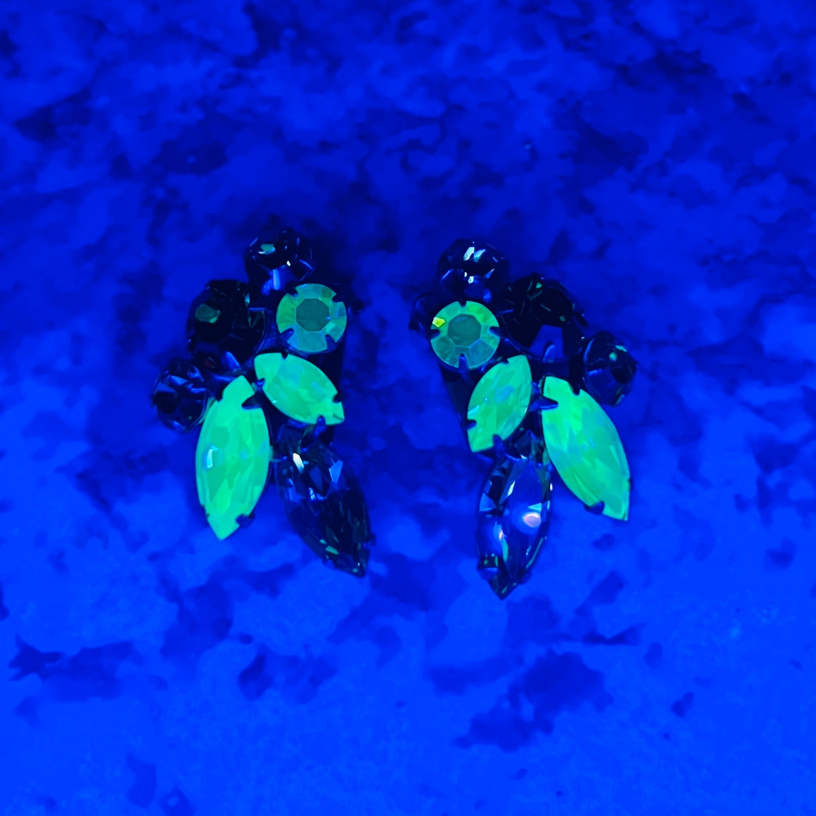 Vintage uranium glass earrings glowing bright green under UV blacklight.