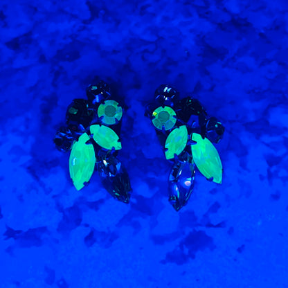 Vintage uranium glass earrings glowing bright green under UV blacklight.