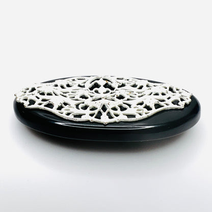 Side view of 1950s enamel brooch showing raised white metal filigree on black base