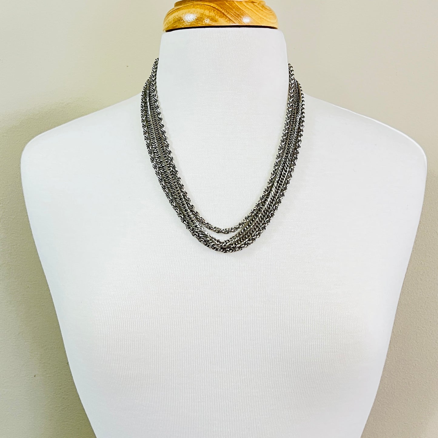 Necklace worn on mannequin showing layered silver chains