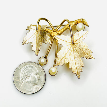 Vintage 1960s Sarah Coventry maple leaf pearl brooch beside quarter for size comparison