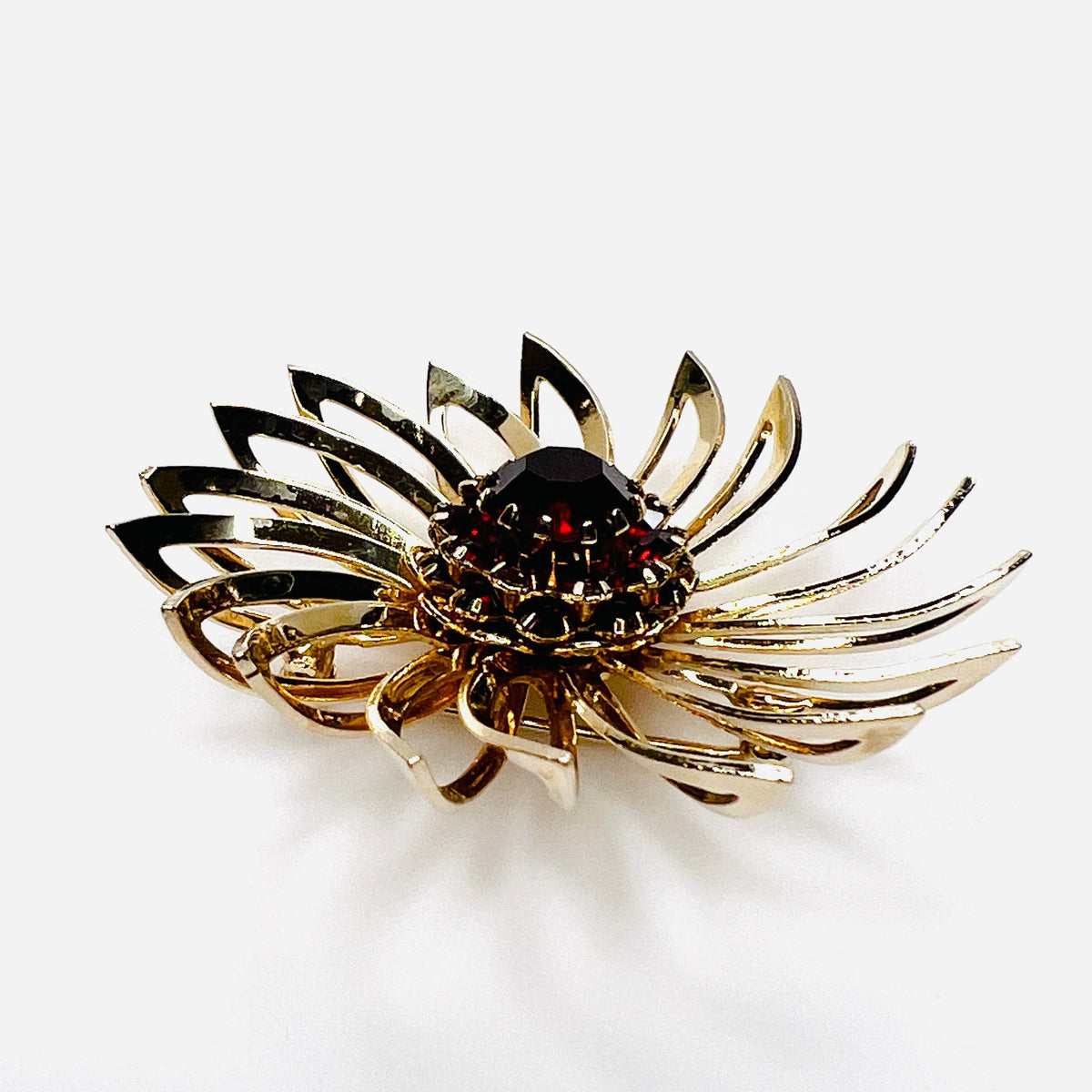 Side view of 1960s gold-tone flower brooch showing raised prong-set red rhinestones