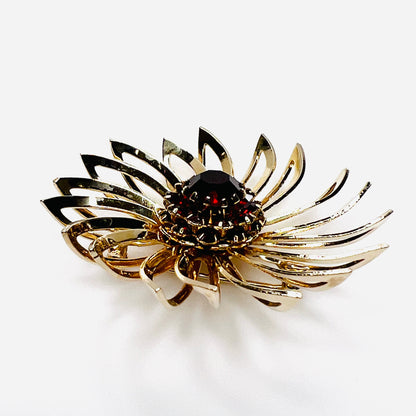 Side view of 1960s gold-tone flower brooch showing raised prong-set red rhinestones