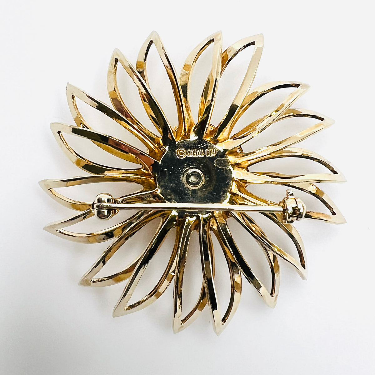 Reverse of signed Sarah Coventry gold-tone flower brooch showing safety pin closure