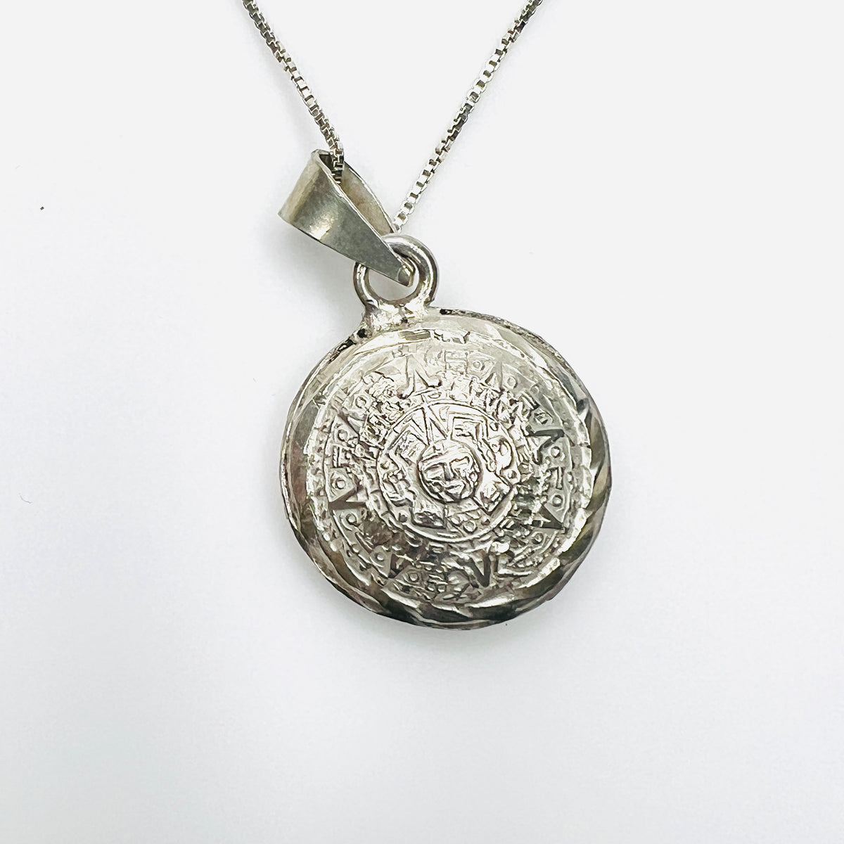 Double-sided silver Aztec pendant showing detailed Sun Stone calendar motif