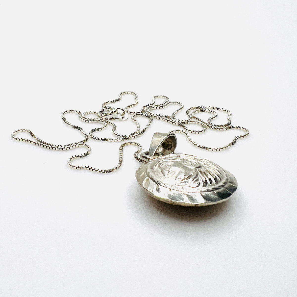 Side view of domed vintage silver Aztec pendant showing dimensional construction