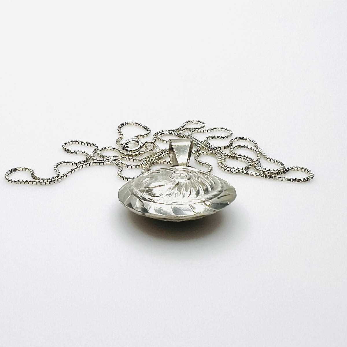 Side view of domed vintage silver Aztec pendant showing dimensional construction