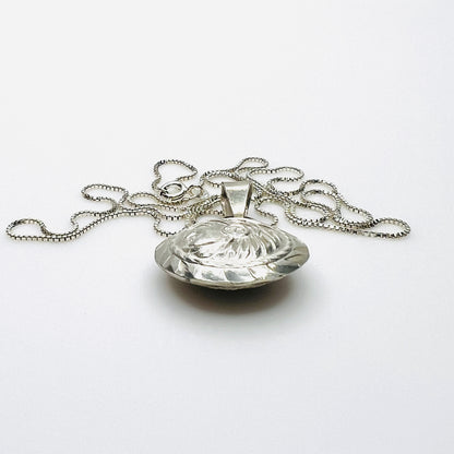 Side view of domed vintage silver Aztec pendant showing dimensional construction