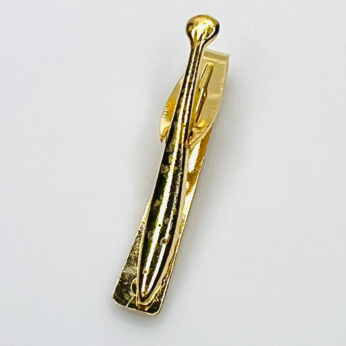 Reverse of vintage West German gold tone tie clip showing spring clip construction and wear