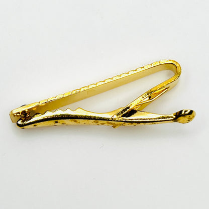 Reverse side viewe of vintage West German gold tone tie clip showing spring clip construction and wear