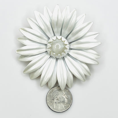 White enamel daisy brooch beside a quarter, showing its 3-inch size and layered flower design.