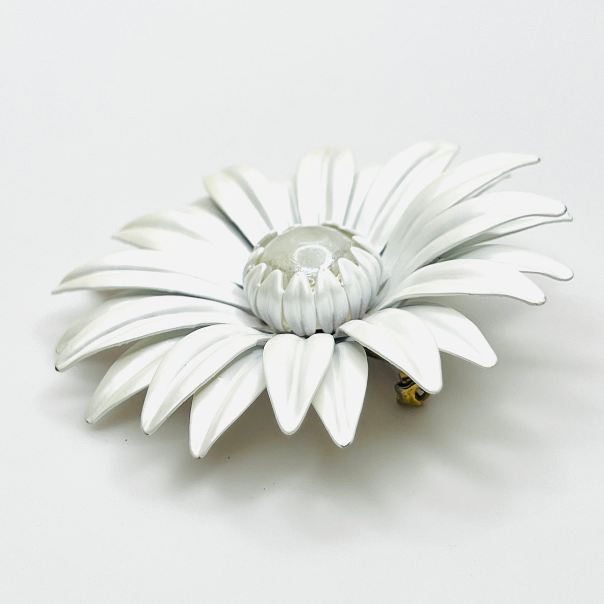 Side view of white enamel daisy brooch showing curved layered petals, Lucite center, and tiny enamel chips.