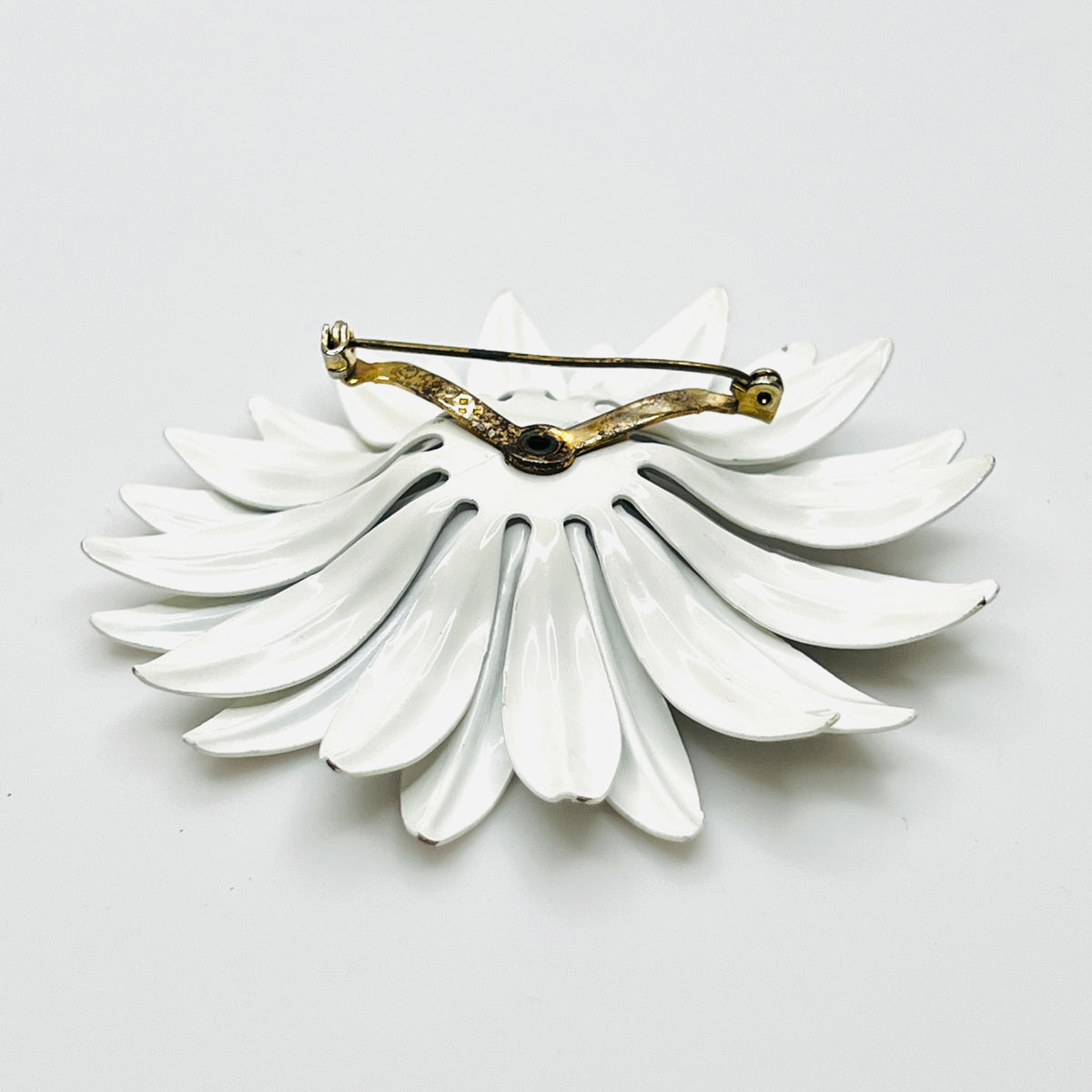Side view of white enamel daisy brooch showing curved layered petals, Lucite center, and tiny enamel chips.