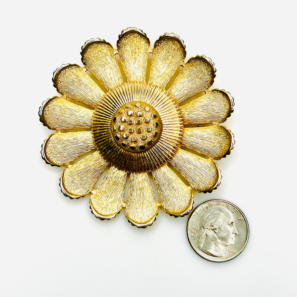 Large Sarah Coventry gold tone daisy brooch shown beside quarter for scale