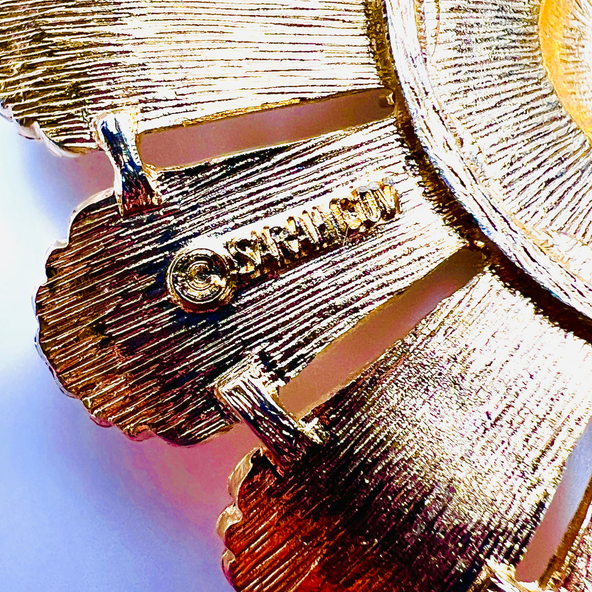Close-up of SARAH COV copyright signature on vintage gold tone brooch