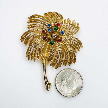 Sarah Coventry gold-tone rhinestone palm spray brooch shown beside quarter for scale